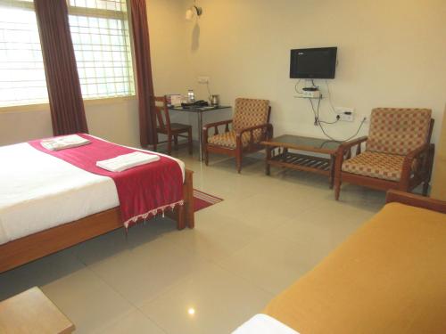 a bedroom with a bed and a table and chairs at KSTDC Hotel Mayura Velapuri Belur in Belūr