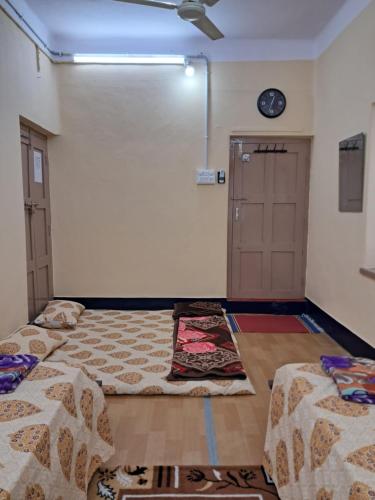 a room with two beds and a clock on the wall at 1 Room for 4 Guests OR 2 BHK for 4 to 10 Guests with AC for Families in Hyderabad