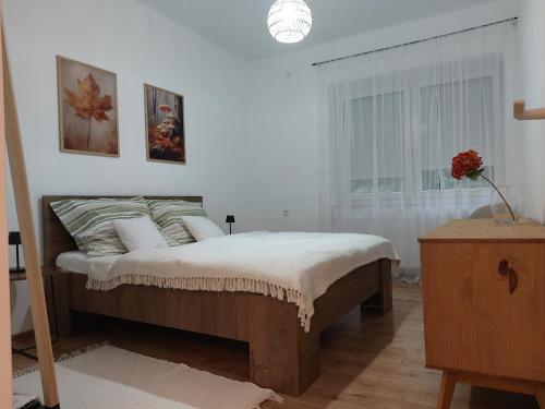 a white bedroom with a bed and a window at Hunor Vendégház in Golop
