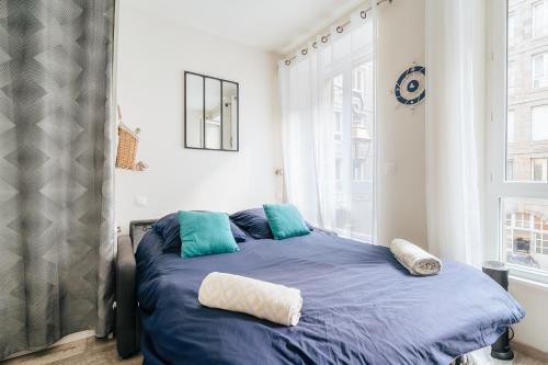 une chambre avec un lit avec des draps bleus et une fenêtre dans l'établissement Capitaine Malouin Saint-Malo intramuros - Port à 30M et plage à 200M, à Saint-Malo