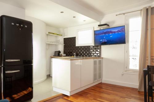 Il comprend une cuisine équipée d'un réfrigérateur noir et de placards blancs. dans l'établissement Charmant appartement - 4 couchages à proximité d'Opéra et des métros, à Paris