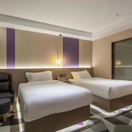 a hotel room with two beds and a chair at Shenzhen Jincheng Hotel in Shenzhen