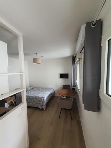 Cette petite chambre comprend un lit et une table. dans l'établissement Studio au calme Espace extérieur Parking gratuit dans la rue, à Grenoble