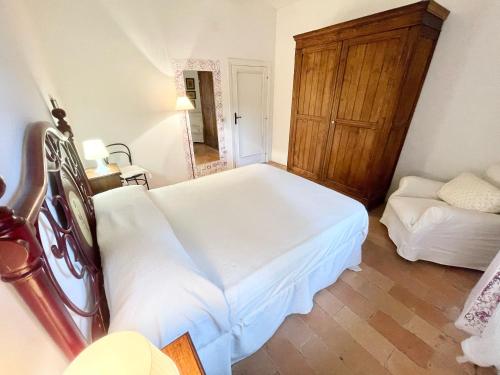 a bedroom with a white bed and a wooden cabinet at Exclusive pool - wondrous views - biological Gardens - pool house - 12 guests in Marzolini