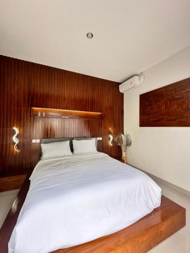 a bedroom with a large white bed with wooden walls at Jimbaran in Jimbaran