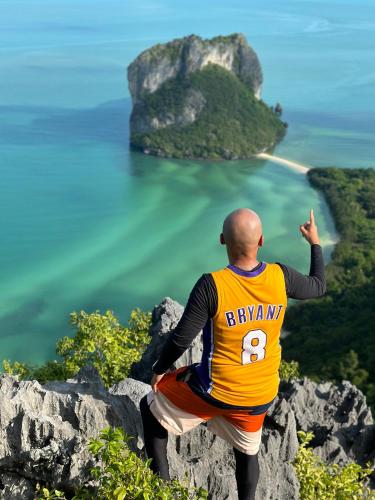 a man sitting on the edge of a mountain looking out at the ocean at Angthong Beach Resort in Koh Phaluai