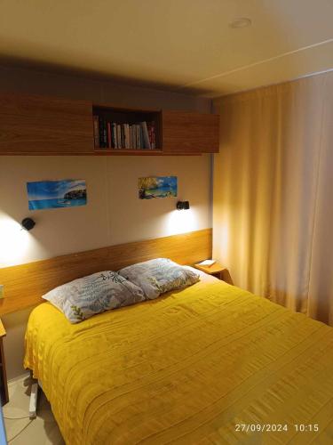 une chambre avec un lit avec une couverture jaune dans l'établissement le logis de la girafe, à Litteau