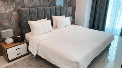 a bedroom with a large bed with white sheets and pillows at Sky Suites-KASS Towers in Okponglo