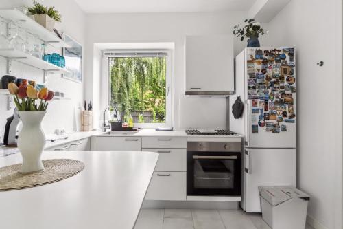 a white kitchen with a refrigerator and a table at Ama Hyg Atelier Copenhagen-Apt-CLOSE TO CITY COPENHAGEN -NEAR AIRPORT-METRO-BEACH in Copenhagen