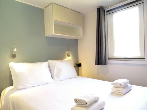 une chambre avec un lit blanc avec des serviettes dessus dans l'établissement La Bohême, à 10min en voiture de Disneyland, à Chalifert