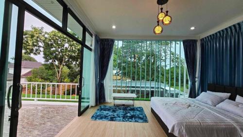 a bedroom with a bed and a large window at Baan Mai-on Poolvilla in Surat Thani