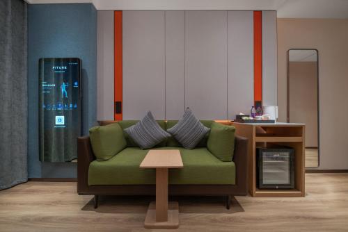 a living room with a green couch and a table at Holiday Inn Express Shangdi Beijing by IHG l Next to The Old Summer Palace & Qinghe Railway Station & Subway l Taxi 15 Minutes to Summer Palace & Peking University & Tsinghua University l 20 Minutes to Badaling Great Wall by Railway in Beijing
