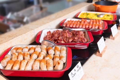 a buffet with trays of sausages and other food at Holiday Inn Express Shangdi Beijing by IHG l Next to The Old Summer Palace & Qinghe Railway Station & Subway l Taxi 15 Minutes to Summer Palace & Peking University & Tsinghua University l 20 Minutes to Badaling Great Wall by Railway in Beijing