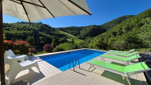 a swimming pool with a table and chairs and an umbrella at Borgo Canapegna - Boschetto - private pool exclusive use in Fabriano