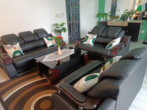 a living room with black leather couches and a table at Villa LE HAVRE DE PAIX in Pahou