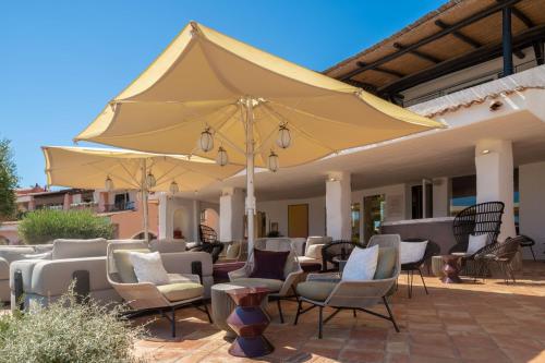 a patio with chairs and a large yellow umbrella at Cervo Hotel,Costa Smeralda Resort in Porto Cervo