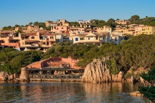 a group of houses on a hill next to a body of water at Cervo Hotel,Costa Smeralda Resort in Porto Cervo