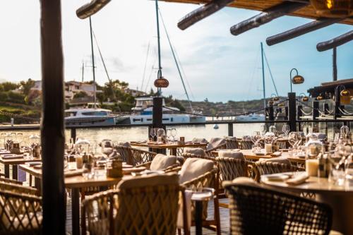 a restaurant with tables and chairs next to a marina at Cervo Hotel,Costa Smeralda Resort in Porto Cervo