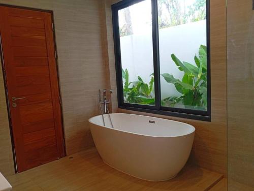 a large white tub in a bathroom with a window at Villa Chacha à Lamai in Lamai