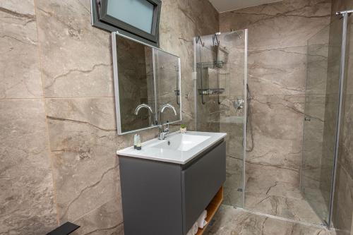 a bathroom with a sink and a shower at וילה קצה ההרים- וילה מדהימה עם בריכה פרטית מול נוף מהמם in ‘Ein el Asad