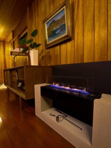 a fireplace in a living room with a wooden wall at 伊豆高原-忘我庵 Cozy Ocean View Villa in Ito