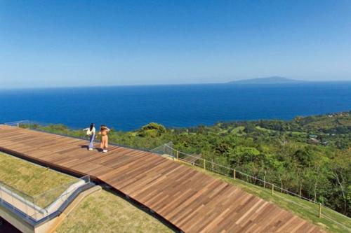 two people standing on a wooden walkway overlooking the ocean at 伊豆高原-忘我庵 Cozy Ocean View Villa in Ito