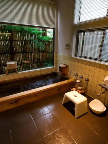 a bathroom with a tub and a toilet and a window at 伊豆高原-忘我庵 Cozy Ocean View Villa in Ito