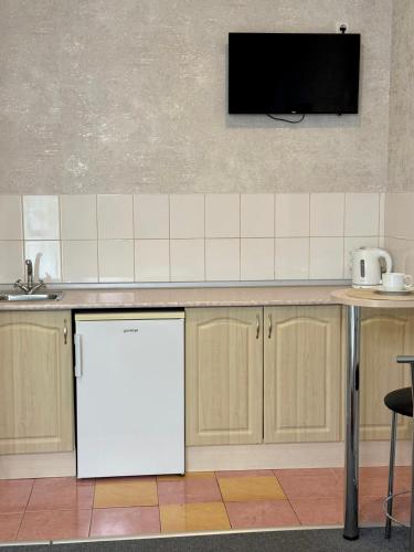a kitchen with a white refrigerator and a tv on the wall at Hotel Vesta in Brovary