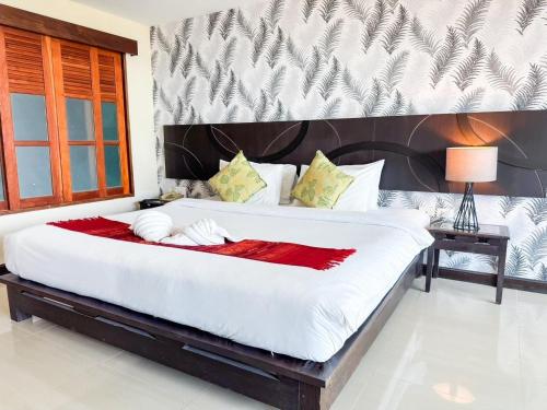 a bedroom with a large white bed with a red blanket at Pattawia Resort & Spa, Pranburi in Pran Buri