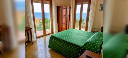 a room with a green bed with a view of the ocean at PARADISO Hotel Ristorante in Reggio Calabria