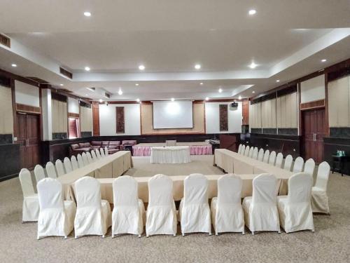 a banquet hall with white chairs and a screen at Pattawia Resort & Spa, Pranburi in Pran Buri