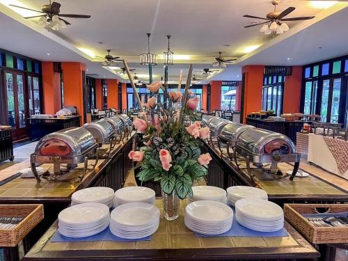 a table with plates and a vase of flowers on it at Pattawia Resort & Spa, Pranburi in Pran Buri