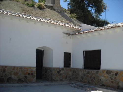 a white building with two doors and a stone wall at Casa-Cueva Las Colleras in Orce