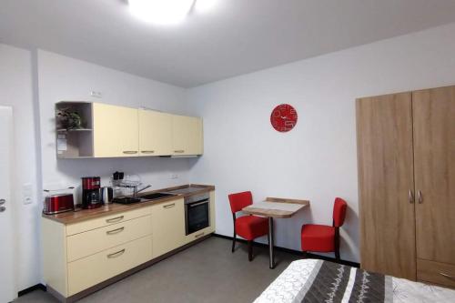 a kitchen with a counter and a table with red chairs at moderne Fewo Peter Bärenstein für 2 Personen in Bärenstein