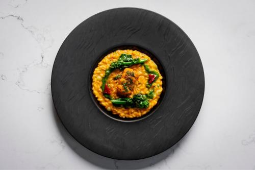a black plate with a dish of food on a table at The Ritz-Carlton, Hong Kong in Hong Kong