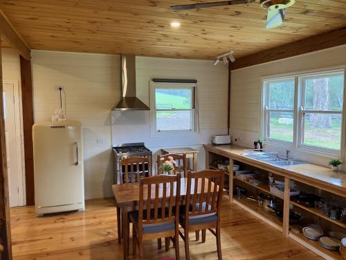 a kitchen with a table and a white refrigerator at Grannies Lane Cottage in Whanregarwen