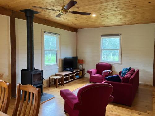 a living room with a woodburning stove and red chairs at Grannies Lane Cottage in Whanregarwen
