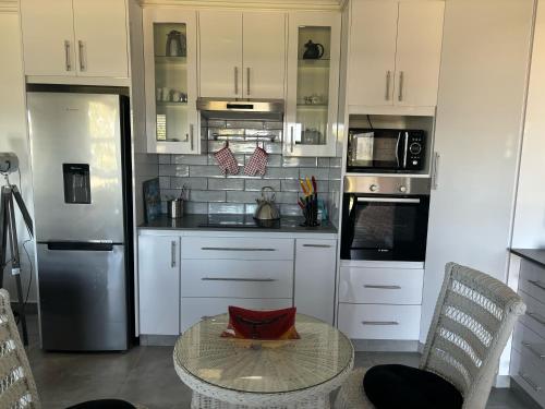 a kitchen with white cabinets and a table with a table at Loerie Lane Accomadation in Groot Brak Rivier