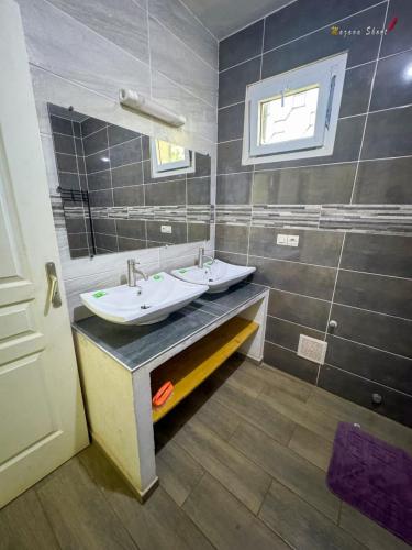 a bathroom with two sinks and a mirror at Villa Esthera Appartement Etage in Antsiranana