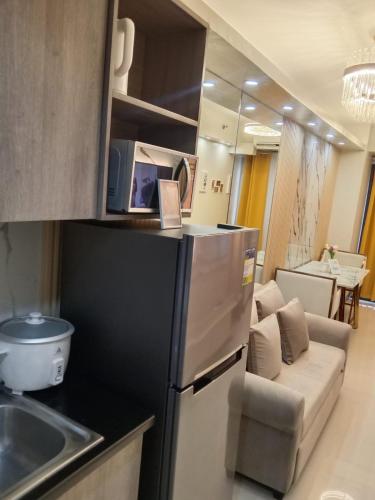 a kitchen with a refrigerator and a living room at The Manor at S Residences in Manila