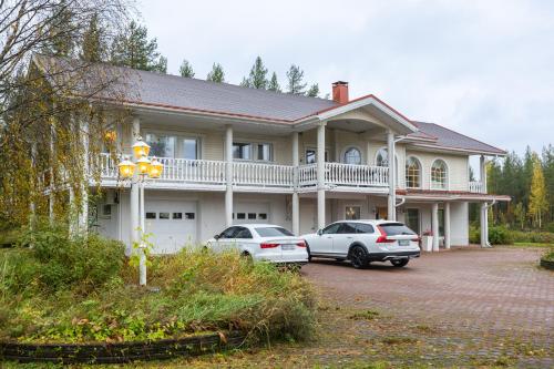 two cars parked in front of a large house at Arctic Countryside House in Rovaniemi