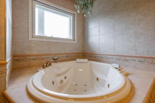 a large white tub in a bathroom with a window at Arctic Countryside House in Rovaniemi