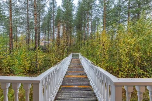 a wooden bridge in the middle of a forest at Arctic Countryside House in Rovaniemi