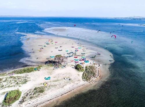 an island with a bunch of people on the beach at Hotel Villaggio Ristorante Pizzeria Museo TANIT in Carbonia