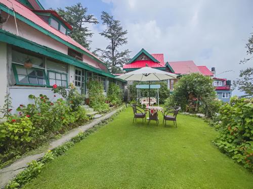 Heritage Aira Holme Estate في شيملا: طاولة وكراسي مع مظلة في الفناء