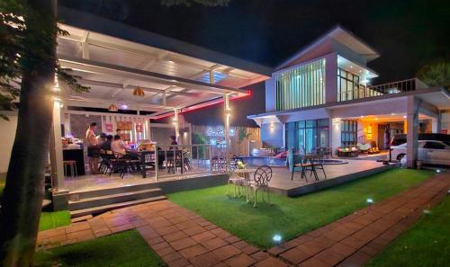 a house at night with people sitting on the patio at Baan Mai-on Poolvilla in Surat Thani