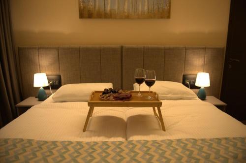 a bed with two glasses of wine and a tray on it at Hotel Takara in Dedoplis Tskaro