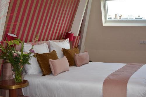 a white bed with a vase of flowers on it at The LIF Boutique in Amsterdam