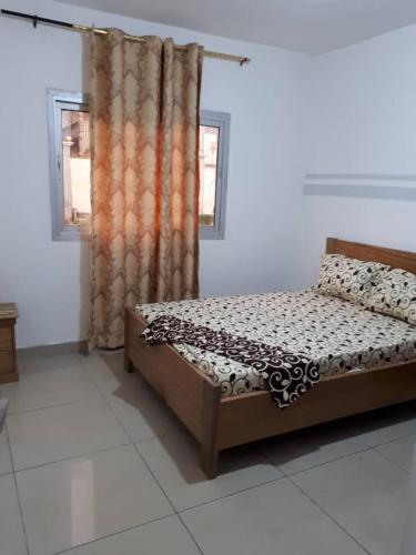Un dormitorio con una cama en una habitación con ventana. en Signorile Jo 3, en Yaoundé