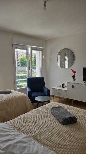 - une chambre avec deux lits, une chaise et un miroir dans l'établissement Appart'City village, à Trappes